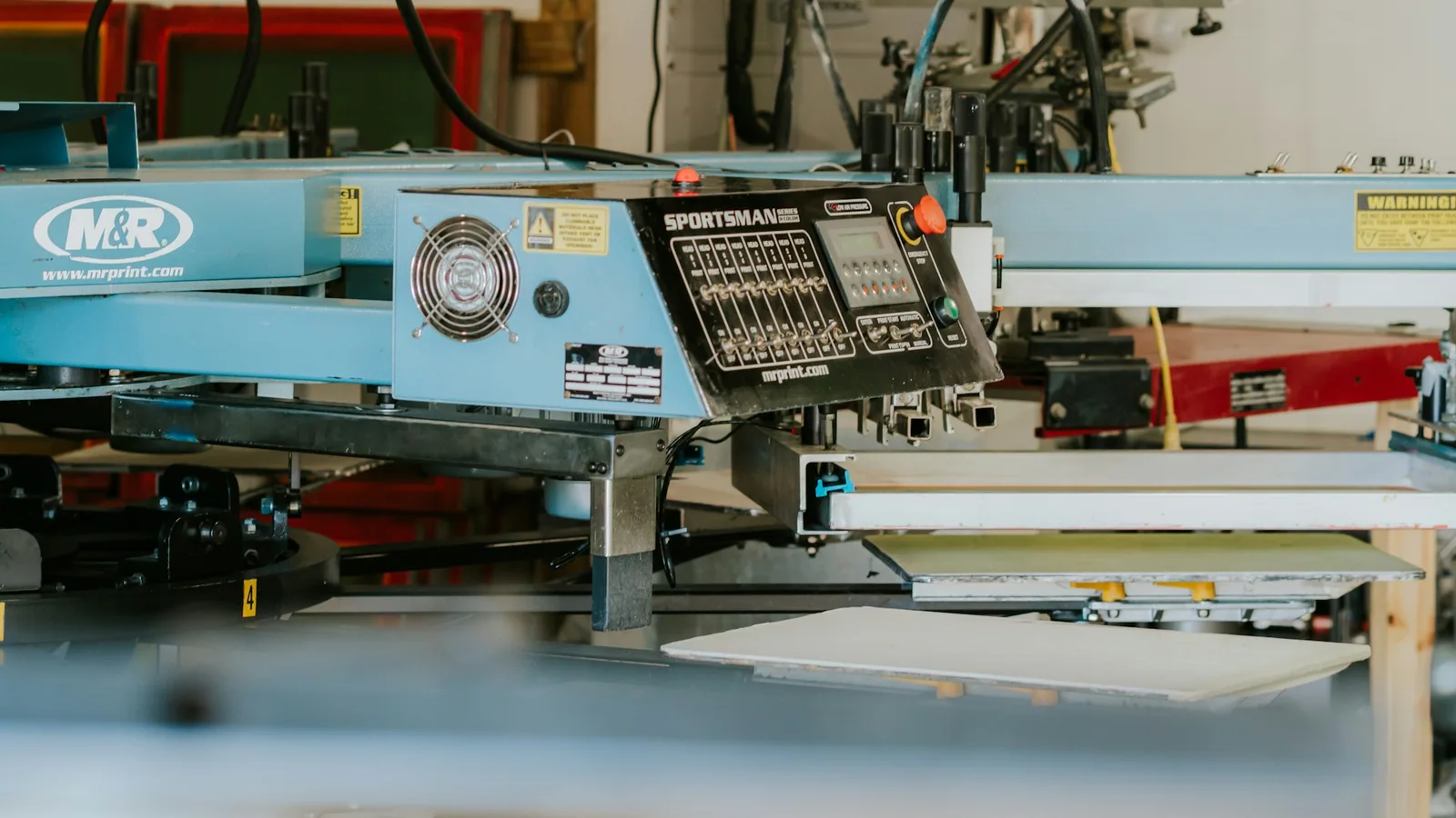 Industrial screen-printing press running branded shirts in a production workshop