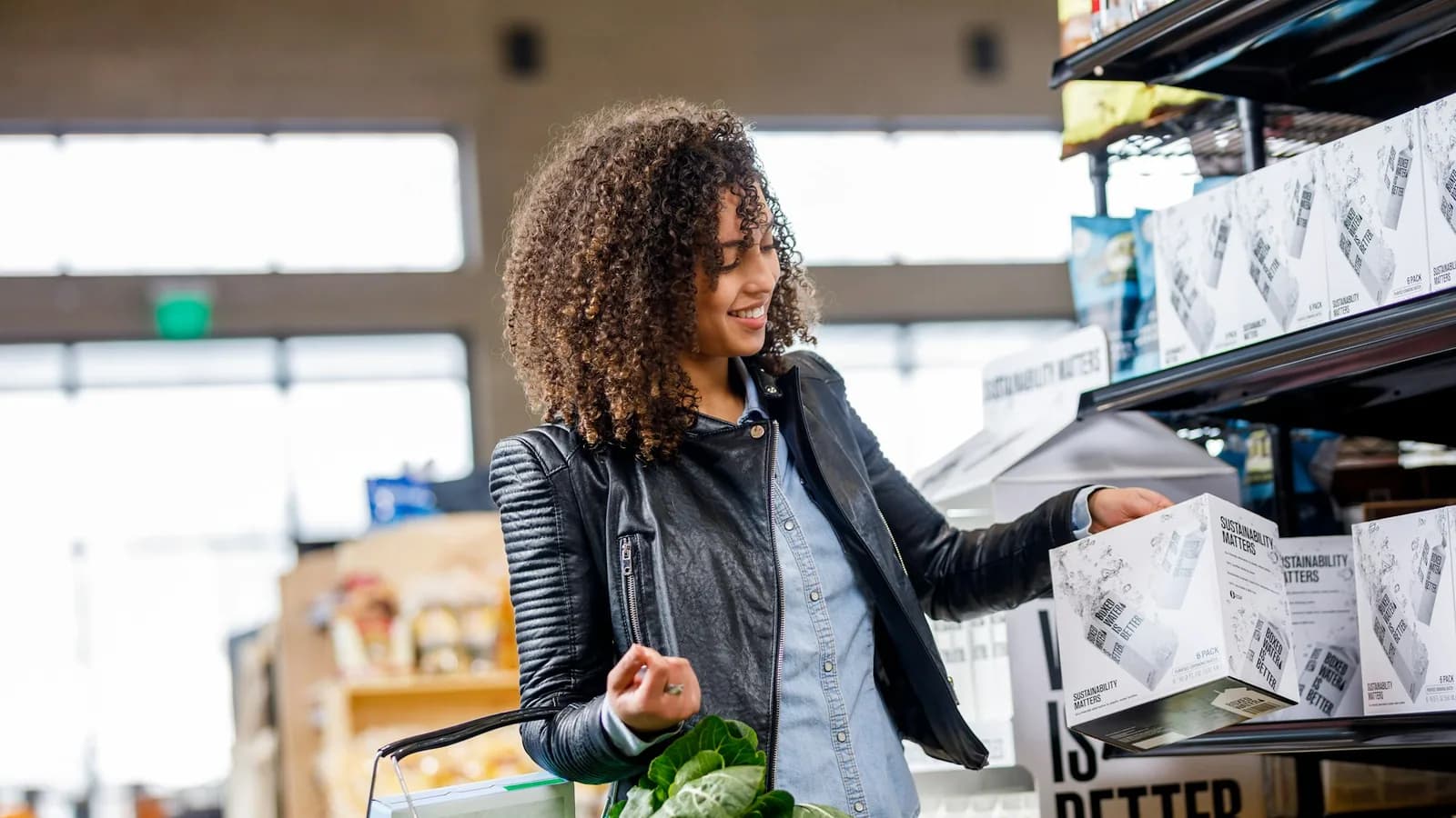 Shopper lifting a product from a shelf while carrying a basket of groceries