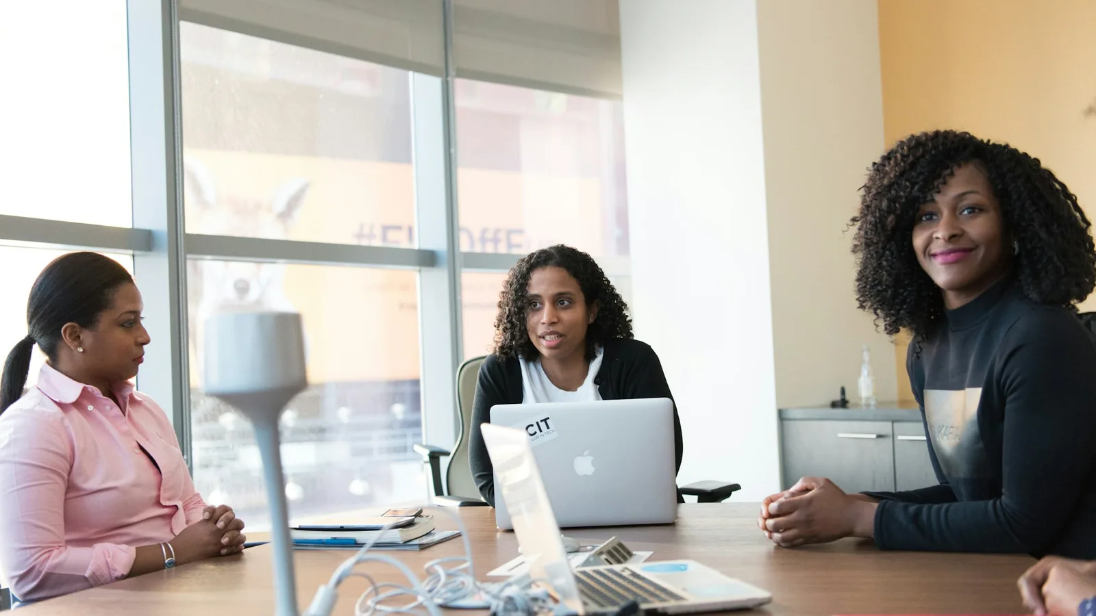 Three colleagues reviewing work together on a laptop in a bright office