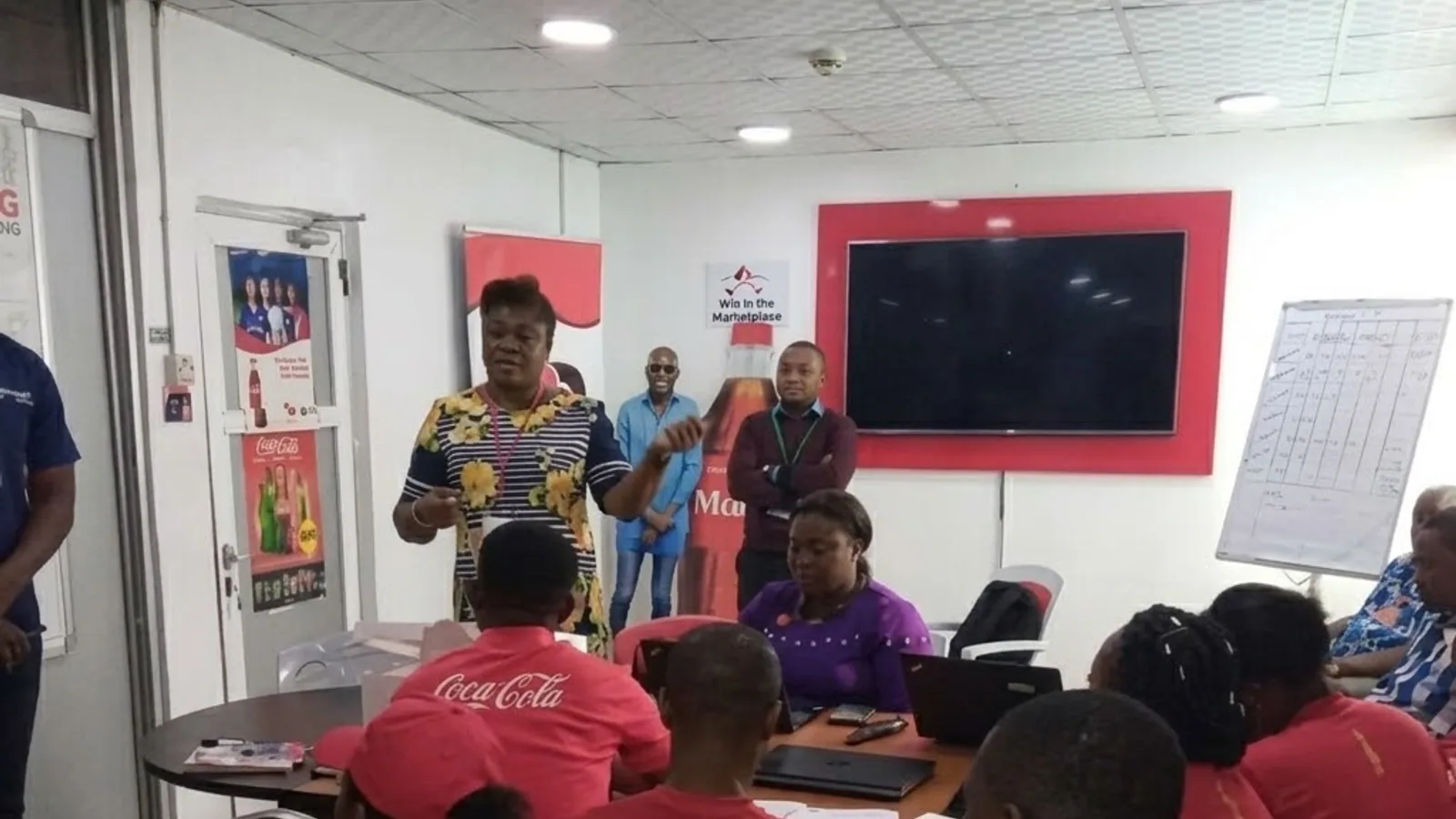 Uniformed field staff briefed in a Coca-Cola branded room before a product activation